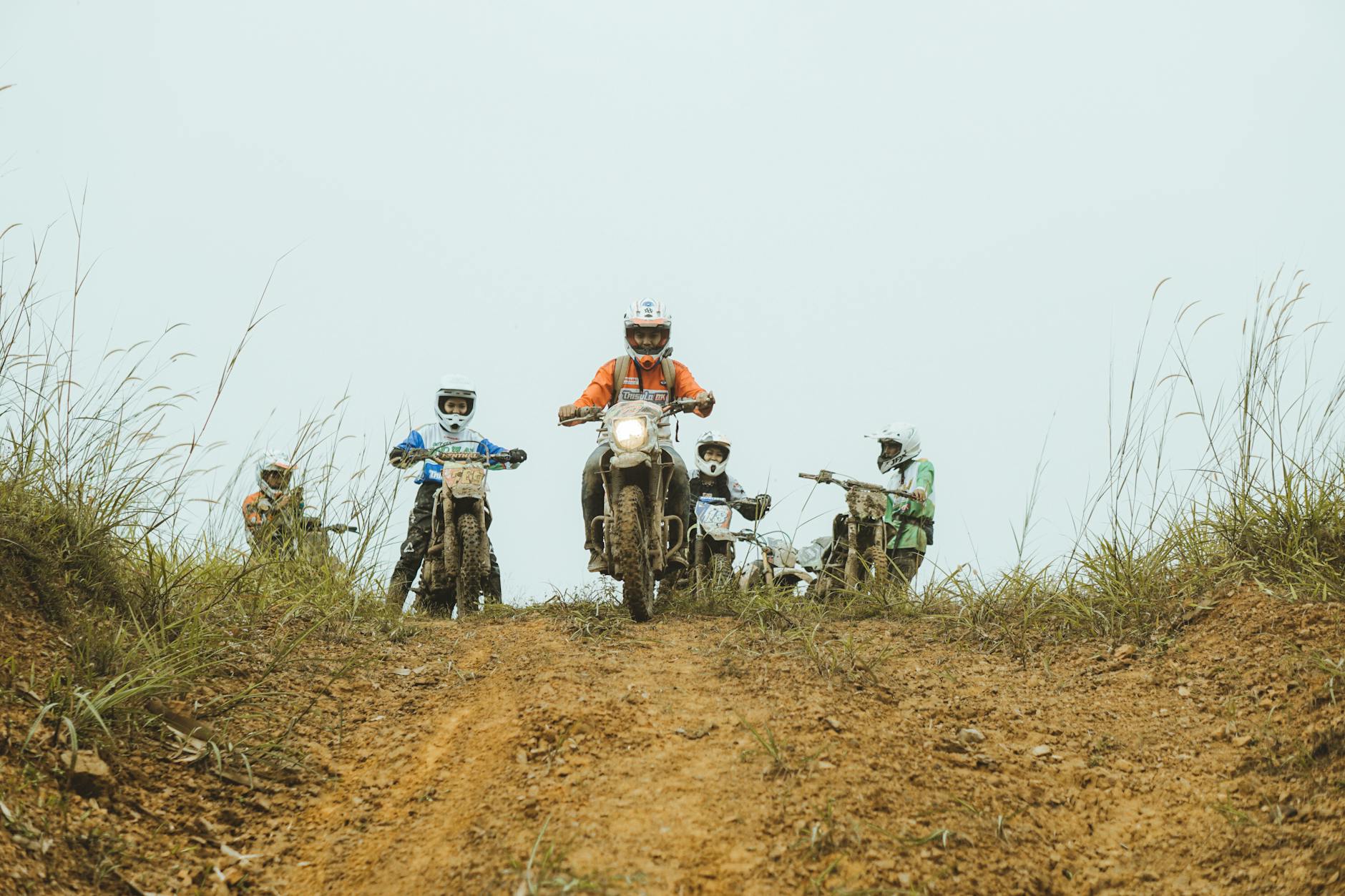 Grupa motocyklistów jedzie w błotnistym terenie enduro