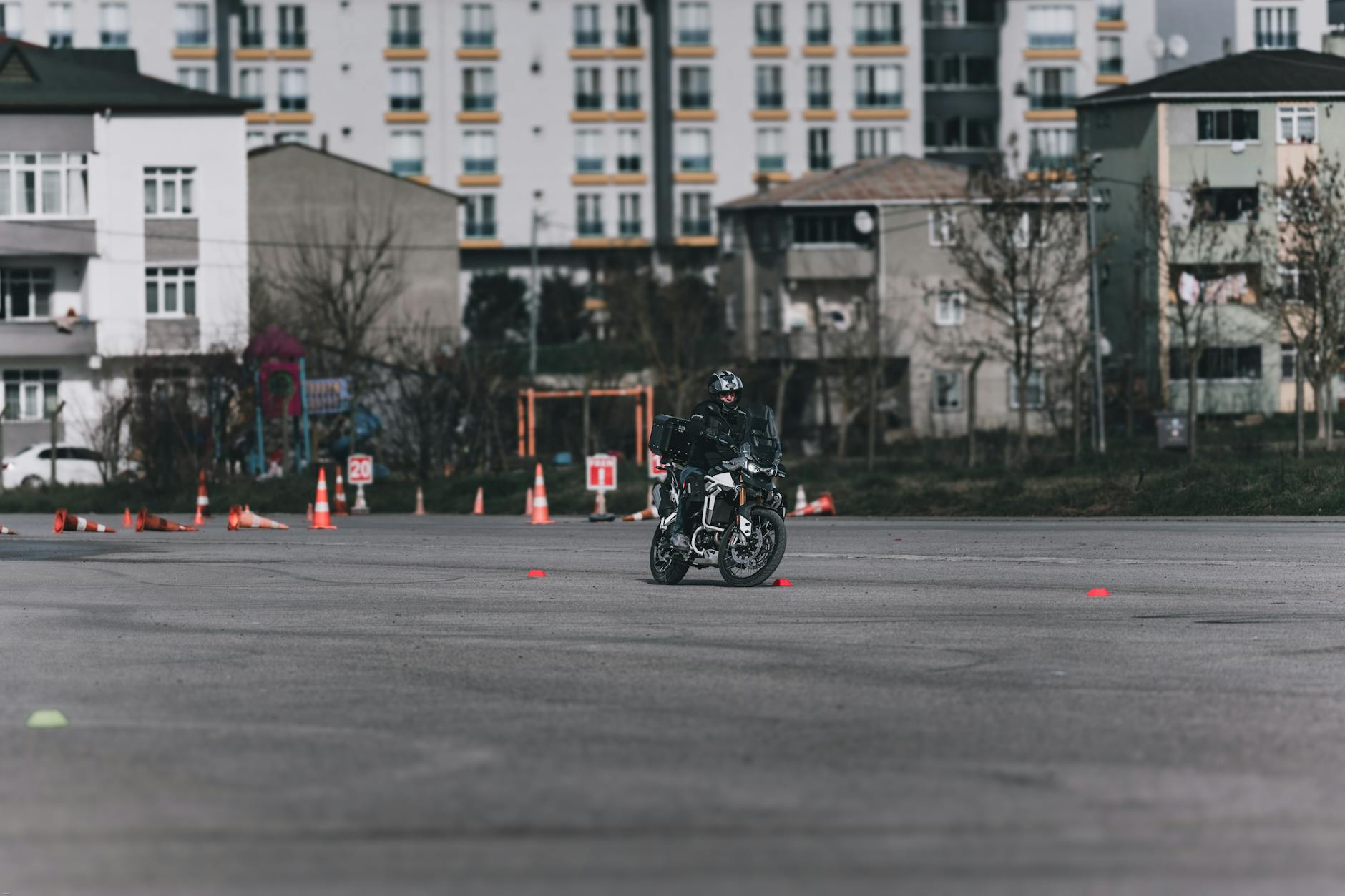 Motocyklista ćwiczący slalom między pachołkami na placu w mieście