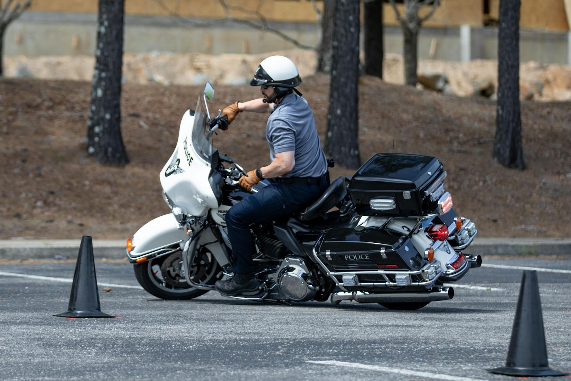 Policjant na motocyklu ćwiczy manewry między pachołkami na placu