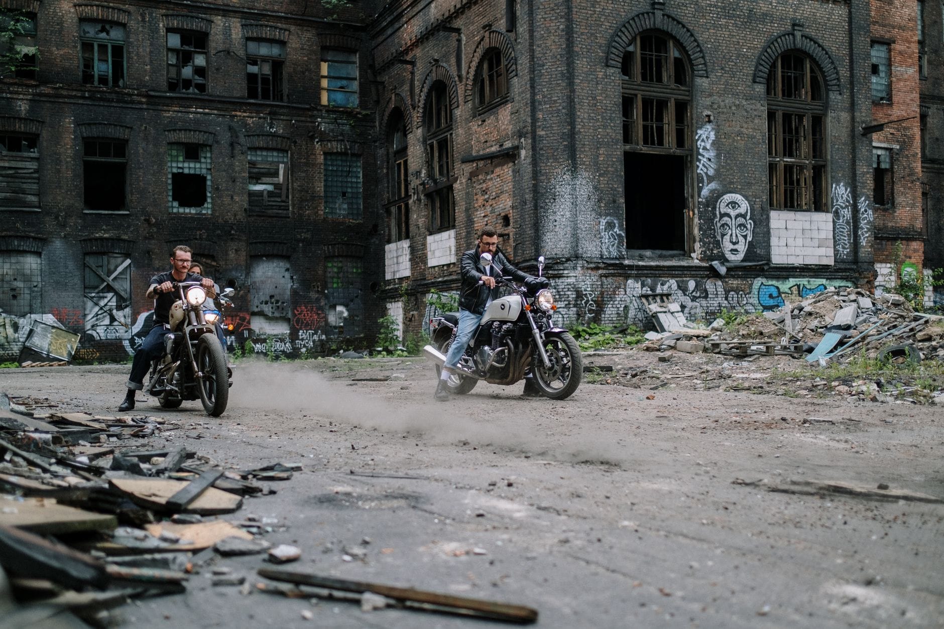 Dwóch motocyklistów jedzie przez opuszczony teren z graffiti